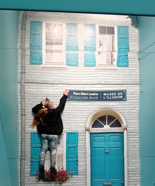 Escalade de la façade d’une maison au musée de l'illusion à Marseille avec une adhérente de l'association Saphir13